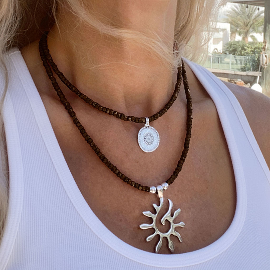 Model trägt Damen-Halsketten mit Glasperlen, Münz- und Sonnenanhänger Ketten Set mit Anhänger Sonne und Münze - Beau Soleil Jewelry