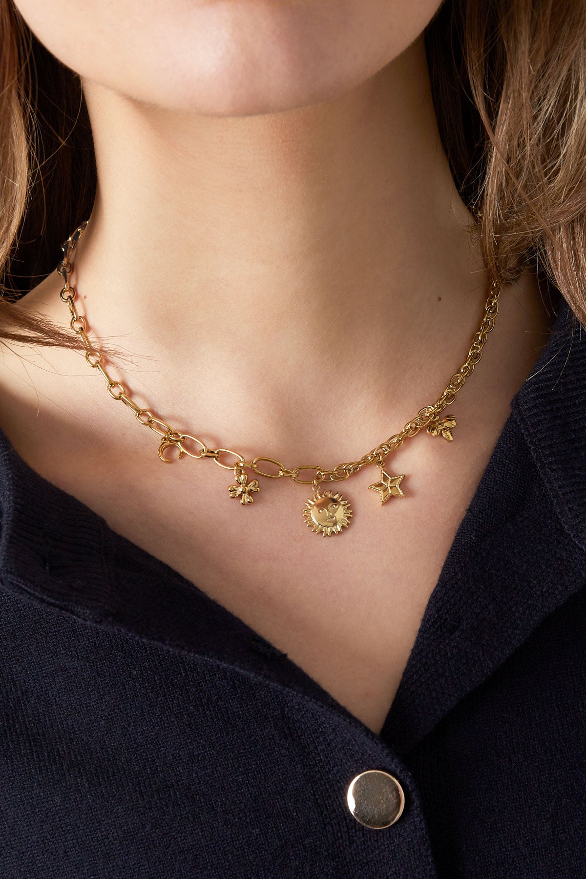 Goldene Charm-Kette angelegt auf Schlüsselbein – kurzer Layering-Look