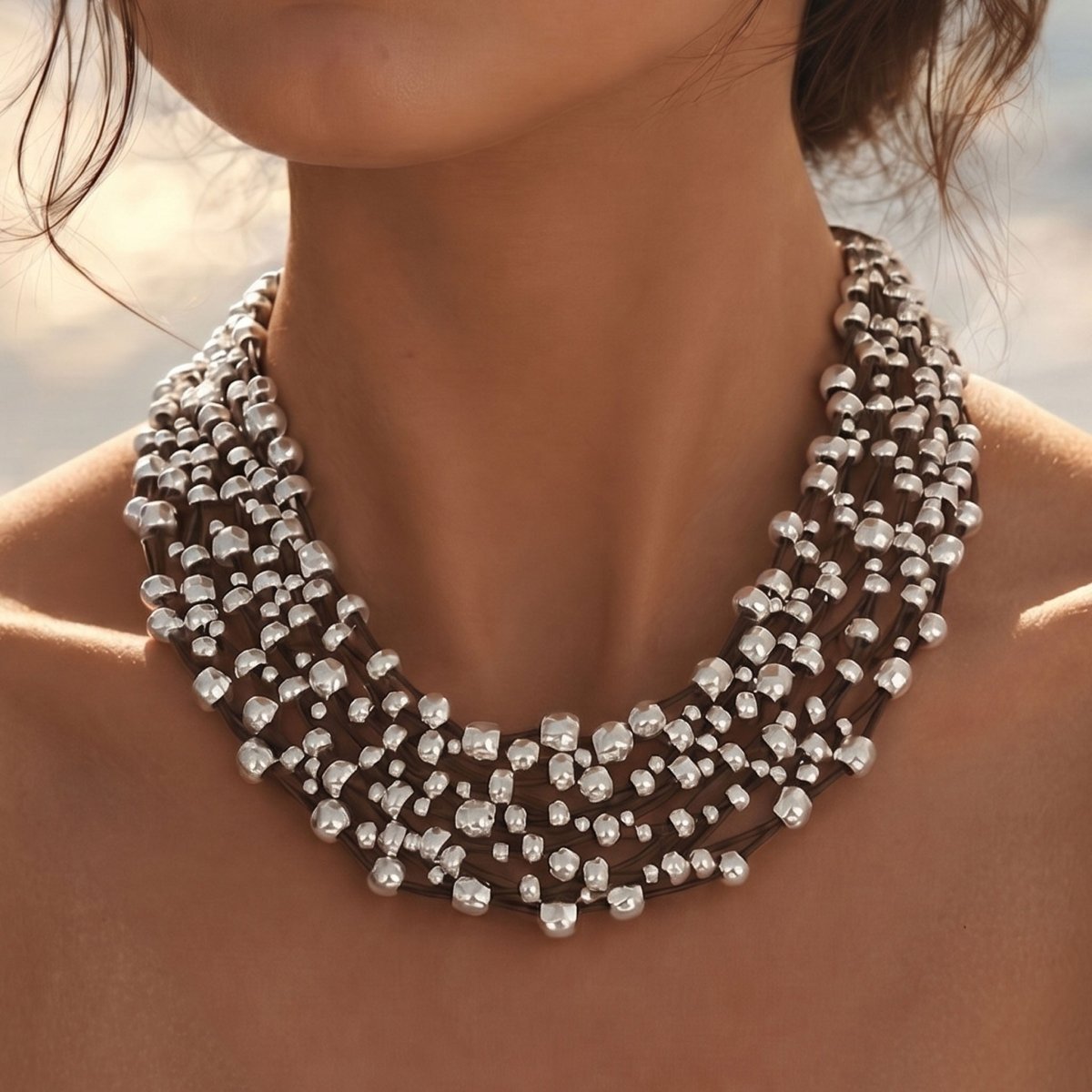 model trägt  mehrreihiges Leder Collier  in schwarz. Hintergrund : blauer Himmel
