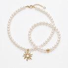 Close-up of the gold-tone jewelry set with shell core pearls, sun pendant and bracelet